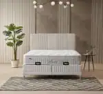 Lit avec coffre et tête de lit rembourrée blanc cassé dans une chambre moderne.