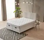 Matelas avec rangement et tête de lit rembourrée dans une chambre lumineuse.